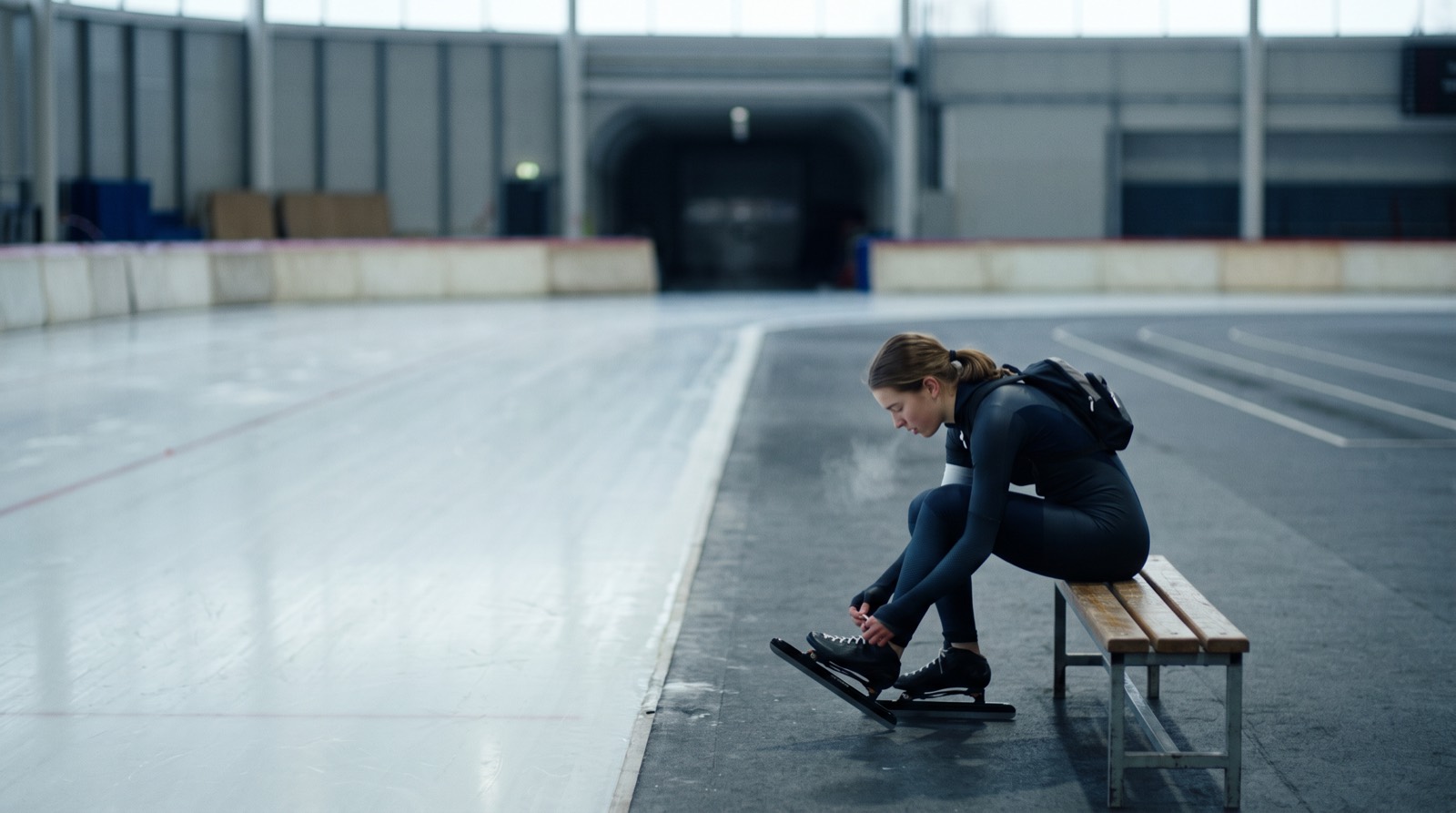 Een schaatsster bindt in haar eentje haar schaatsen onder in een leeg ijsstadion voor zonsopkomst